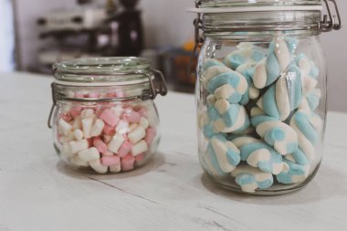 Sakızlı cam kavanozlar, marşmelovlar beyaz ahşap üzerine pembe beyaz mavi ve kahve arkaplan