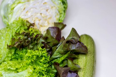 Taze, yeşil sebzelerle dolu bir hayat. Kabak, taze lahana, marul. Gri bir arka planda. Sol tarafta yer almaktadır. Mesaj için yer var. Dikey fotoğraf. Yukarıdan görünüşü.