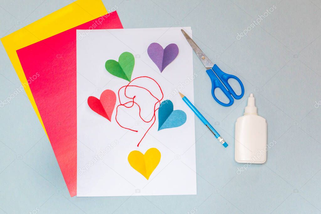 Step-by-step instructions. DO IT YOURSELF. Do it yourself. Postcard made of colored paper and cardboard. Colored hearts on yellow cardboard. On a gray background. Vertical photo. The view from the top