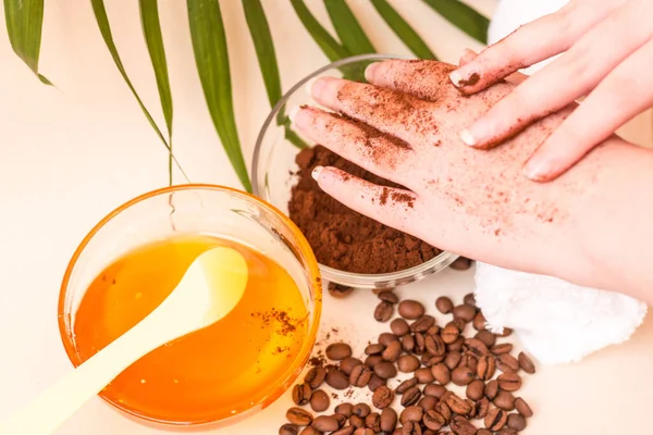 Spa care at home. Women\'s hands make a scrub with ground coffee. Scrub of coffee and honey. Bright background. Space for text. Horizontal photo. The view from the top