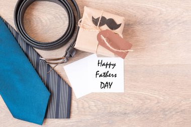 İki mavi kravat, deri, siyah kuşak, ahşap bir arka planda el işi kağıdında hediye. Siyah bıyık. Ahşap arka plan. Yukarıdan manzara. Metin için boşluk