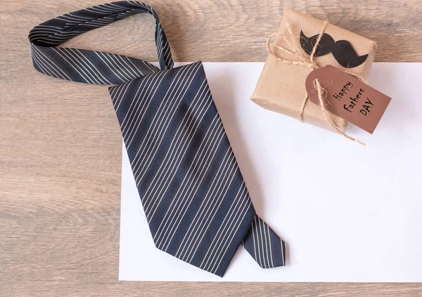 贈り物 青いネクタイ そして父親のカード 白い紙の上にストライプのネクタイ お父さんのための最高の品質の贈り物 黒ひげ 木製の背景 上からの眺め テキストのスペース — ストック写真