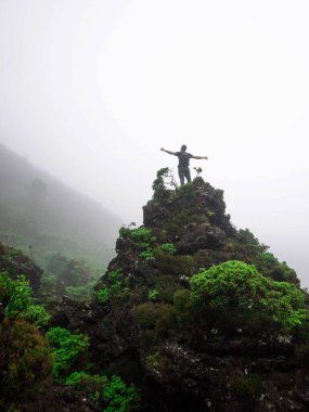 Joven en la cima de una pequea montaa en entorno nublado