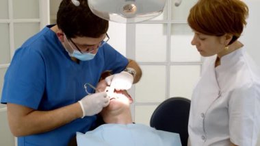 Diş sağlığı kliniği. Doktor dişçi, dişçi kliniğindeki hastaya bakar. Diş hekimi ve ortodontist. Diş tedavisi ve ısırık düzeltmesi.