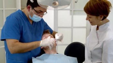Diş sağlığı kliniği. Doktor dişçi, dişçi kliniğindeki hastaya bakar. Diş hekimi ve ortodontist. Diş tedavisi ve ısırık düzeltmesi.