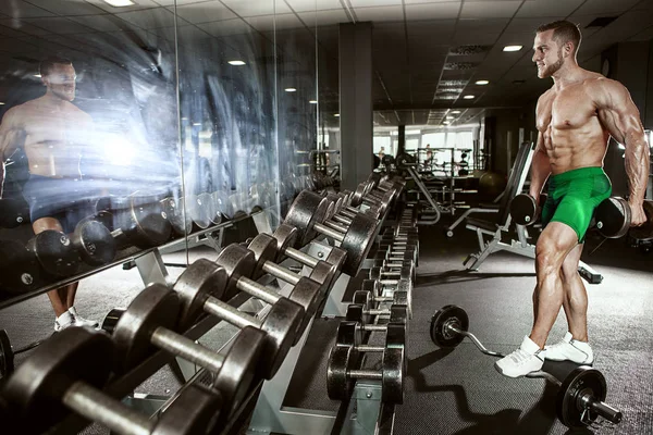 用哑铃锻炼肌肉的健美运动员家伙 — 图库照片
