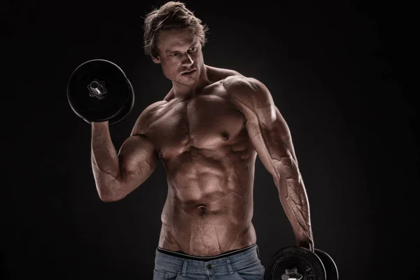 Muskulös bodybuilder killen gör övningar med hantlar — Stockfoto