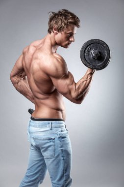 Muscular bodybuilder guy doing exercises with dumbbells clipart