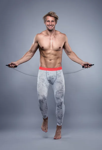 М'язистий культурист хлопець робить вправи зі стрибком мотузки — стокове фото
