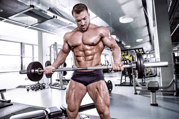 Muscular bodybuilder guy doing exercises with dumbbell