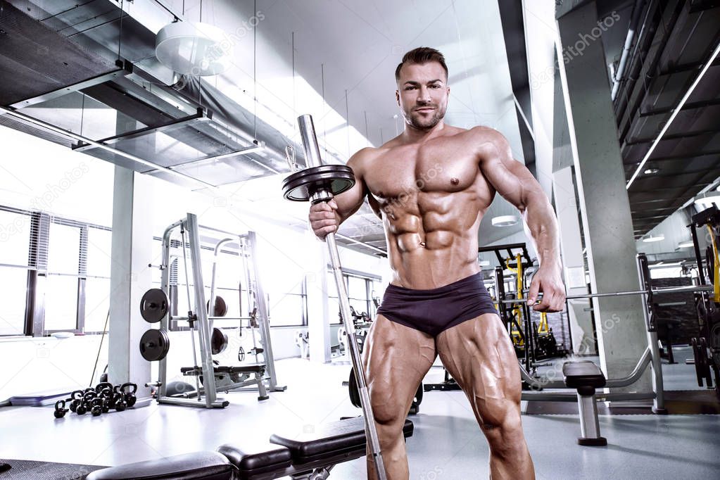 Muscular bodybuilder guy doing exercises with dumbbell