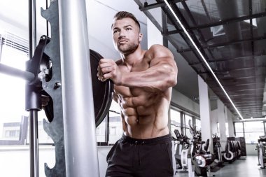 Multip üzerinde halter alıştırmalar yapan kaslı vücut geliştirmeci adam