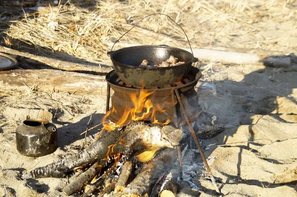 outdoor dinner - fried meat in a pan on a fire