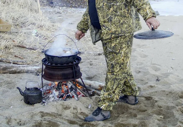 outdoor dinner - fried meat in a pan on a fire