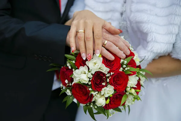 Mãos de um casal recém-casado em um buquê de casamento — Fotografia de Stock