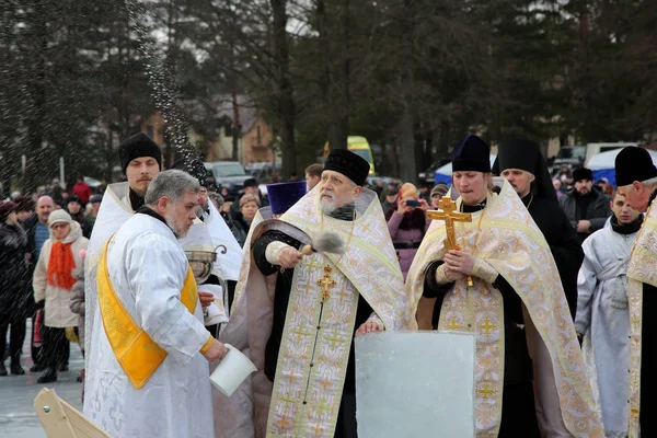 Священик освячує льоду отвір на святкування Водохреща Господнього — стокове фото