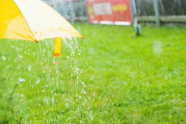 Gotas de lluvia cayendo de un paraguas amarillo — Foto de Stock