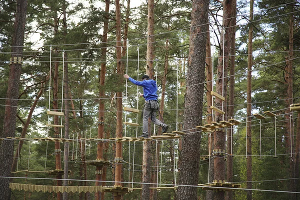 Mann klettert in Sicherheitsausrüstung in Abenteuer-Seilpark — Stockfoto