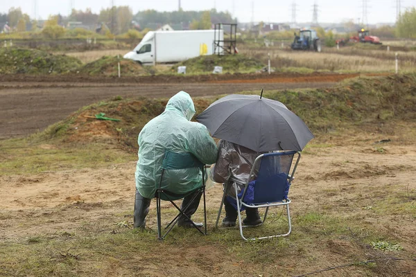 Menschen sitzen in Regenmänteln — Stockfoto