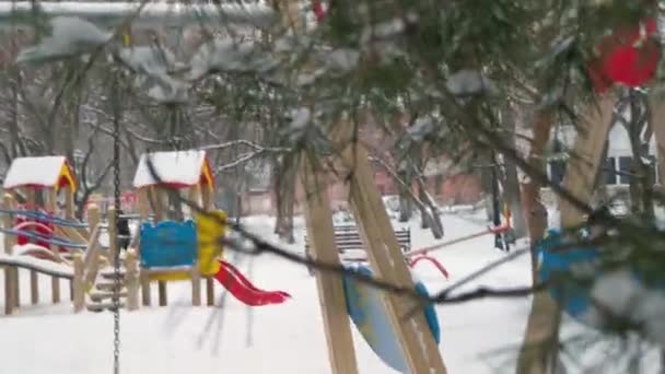 通行人が遊び場を通り過ぎる 雪が降ってる 木の後ろから男の観察 — ストック動画