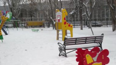 Bahçede insanların olmadığı bir oyuncak. Karda çocukların arabası rüzgardan sallanıyor..