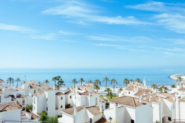 Deniz kenarındaki evler Palmiye ağaçları ve mavi gökyüzü