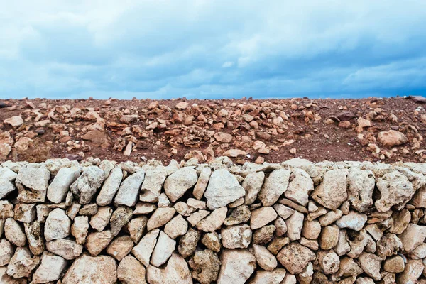 Abstract organic horizontal composition of red earth, white rocks and blue sky with clouds