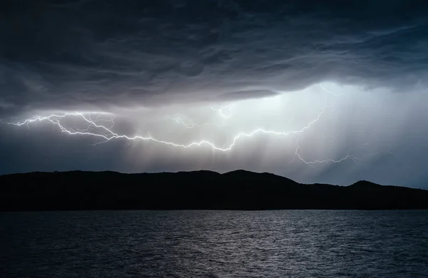 Big gray cloud and thunderstorm over an island in the sea at night