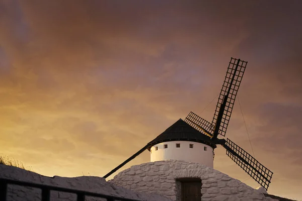 Big windmill under a cloudy orange sky at sunset.