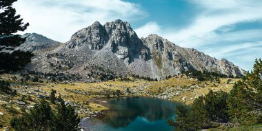 Pireneler 'deki bir dağın eteğinde mavi bir gölün panoramisi
