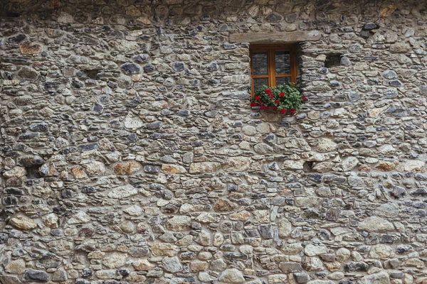 Window with geraniums on wall of typical stone house