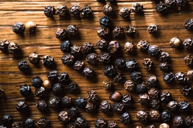 Kırsal ahşap arka planda yatay kompozisyonda siyah karabiberlerin makro fotoğrafları.