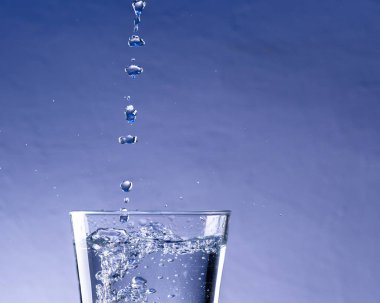 Su damlalarının mavi arkaplanlı cama düşüşünün ayrıntıları