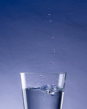 Damlaların mavi arkaplanlı suya düşüşünün ayrıntıları-