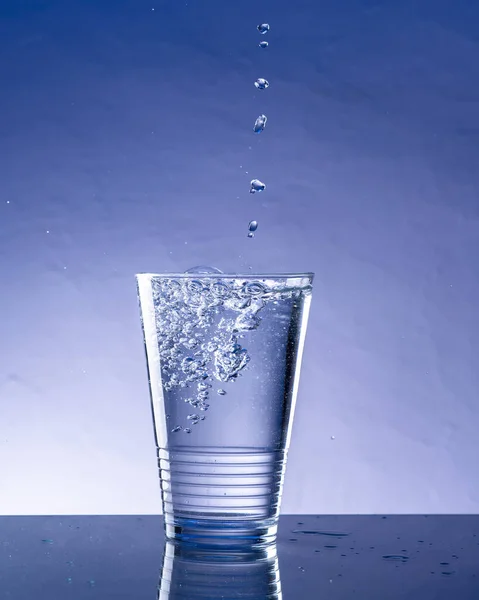 Water Drops Falling Glass Cup Blue Background — Stock Photo, Image