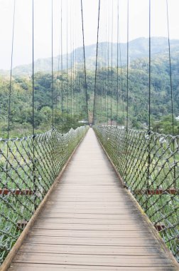 Metal çitli ahşap asma köprü ve kırmızı kemer.