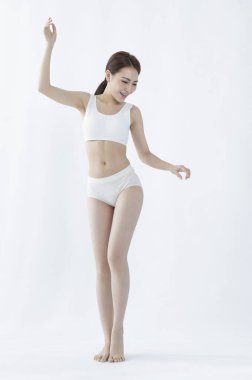 İç çamaşırlı genç kadın beyaz arka planda poz veriyor