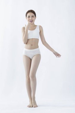 İç çamaşırlı genç kadın beyaz arka planda poz veriyor