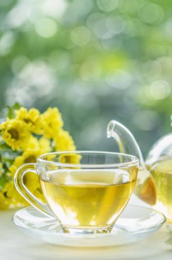 Tahta bir masada çiçekli bir fincan bitki çayı.