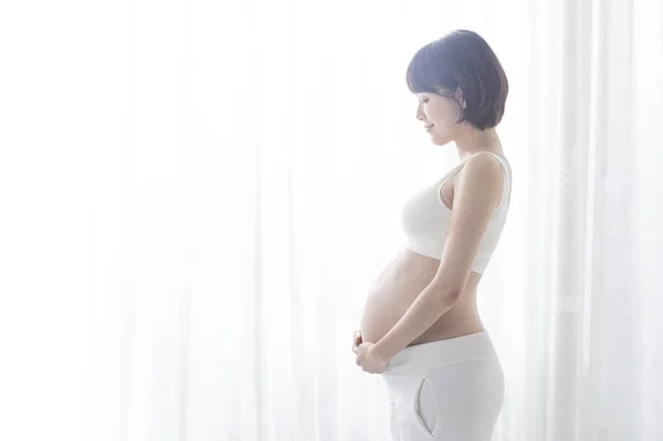 年轻的亚洲孕妇站在半圈 紧紧抓住肚子 — 图库照片