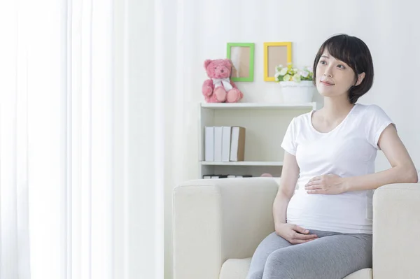 若いです妊娠中のアジアの女性はアームチェアに座って — ストック写真