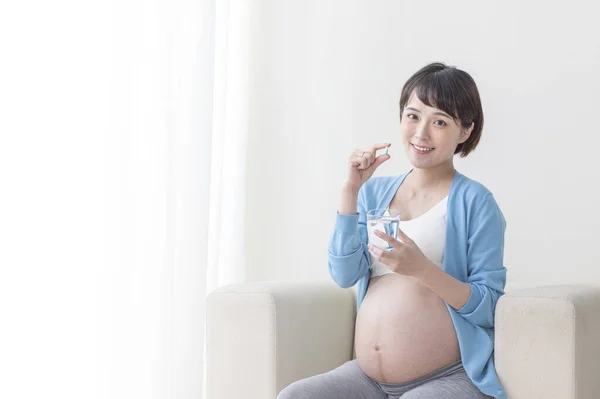 年轻的亚洲孕妇吃避孕药 — 图库照片