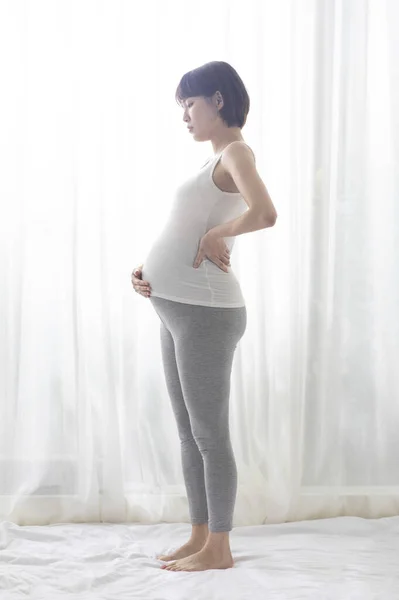 年轻的亚洲孕妇站在半圈 紧紧抓住肚子 — 图库照片