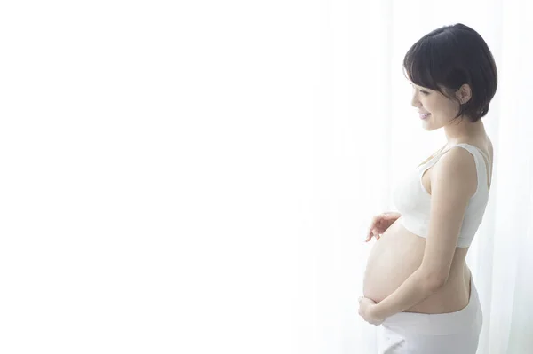若いです妊娠中のアジアの女性立ち半分ターンと彼女の腹にしがみつく — ストック写真
