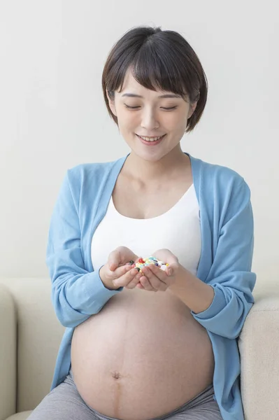 正在吃药的年轻亚洲孕妇 — 图库照片