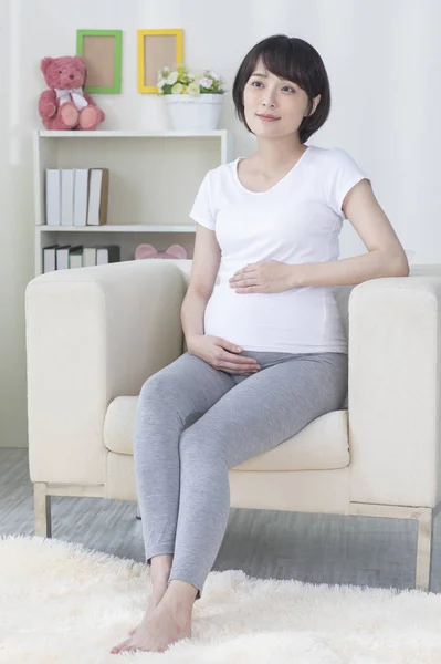 若いです妊娠中のアジアの女性はアームチェアに座って — ストック写真