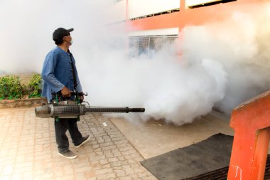 Bir adam Zika virüsünün sivrisinek taşıyıcısını öldürmek için dezenfekte sivrisinekleri kullanıyor ve okulda dang humması salgını ve yağmur mevsiminde evler. Duman sivrisinekleri öldürmek için kullanılır..