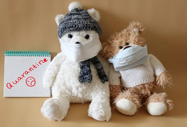 Soft toys bears in medical masks on a beige background. Schools and kindergartens are under quarantine due to the pandemic of coronavirus Covid-19. Home schooling. Quarantine sign written by a child\'s hand.