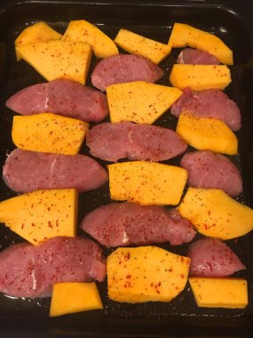 Çiğ hindi ya da tavuk göğsü dilimleri ve fırında pişirmeye hazır baharatlı olgun balkabağı. Lezzetli ve sağlıklı bir yemeğin tarifi. Adım adım.