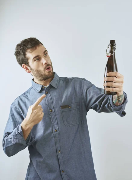 Homem Aponta Para Uma Garrafa Cerveja Com Gesto Expressivo Ele — Fotografia de Stock